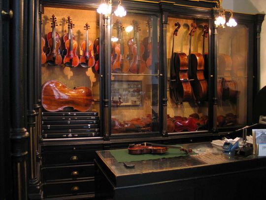 Theke des Geigenateliers mit Streichinstrumenten im Hintergrund